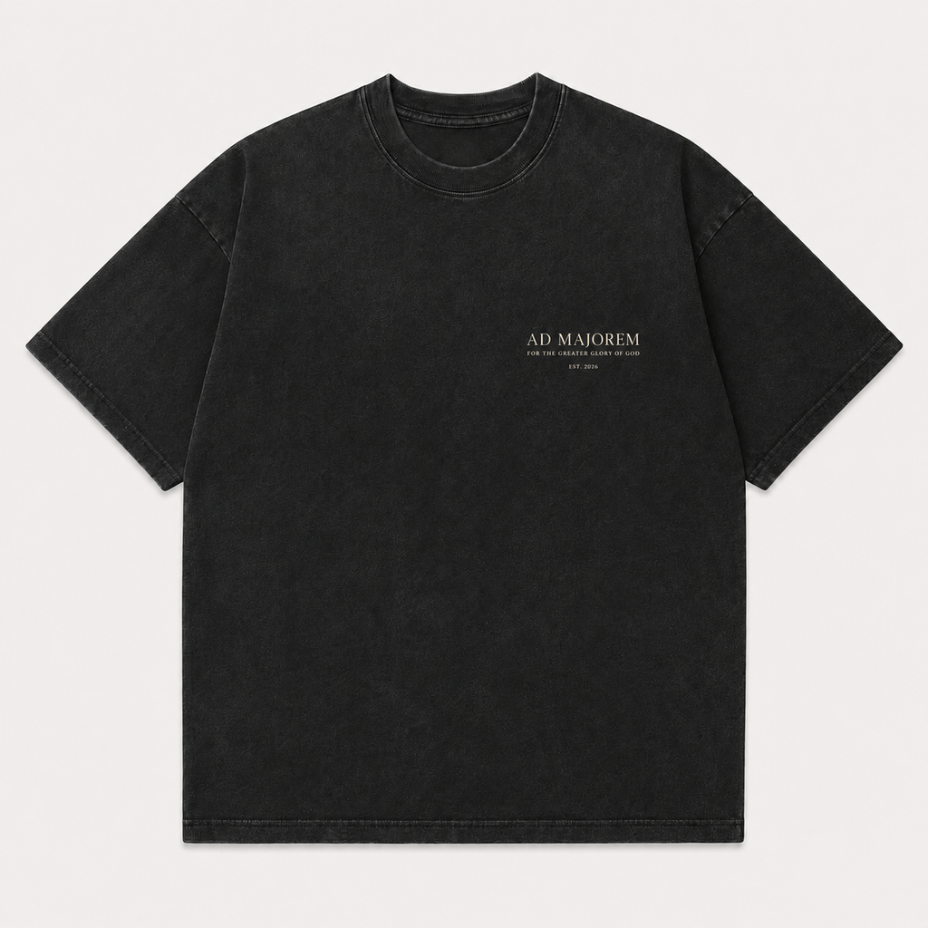 A black washed short-sleeve t-shirt with 'AD MAJOREM' printed in white on the left chest, displayed flat against a light gray background.