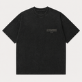 A black washed short-sleeve t-shirt with 'AD MAJOREM' printed in white on the left chest, displayed flat against a light gray background.