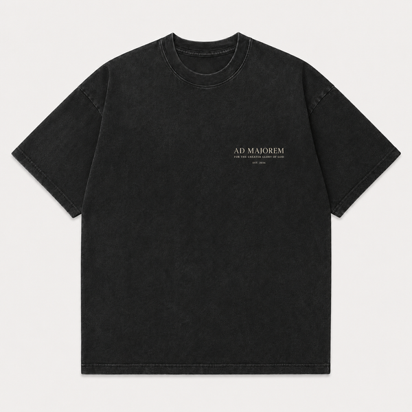 A black washed short-sleeve t-shirt with 'AD MAJOREM' printed in white on the left chest, displayed flat against a light gray background.